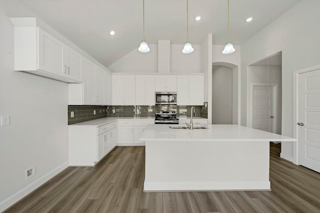 kitchen with sink, white cabinets, a center island with sink, appliances with stainless steel finishes, and decorative light fixtures