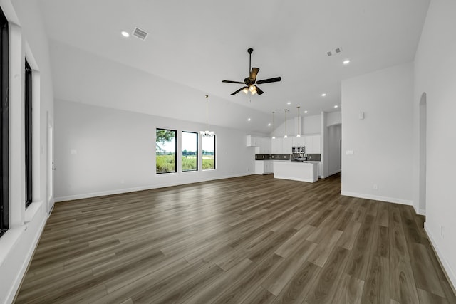 unfurnished living room featuring ceiling fan with notable chandelier and dark hardwood / wood-style flooring