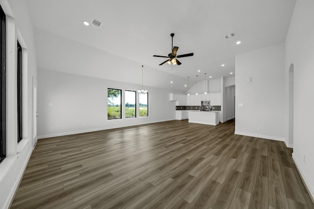 801 Rd 5812, Cleveland, TX 77327 - unfurnished living room featuring a ceiling fan, vaulted ceiling, arched walkways, dark wood finished floors, and recessed lighting