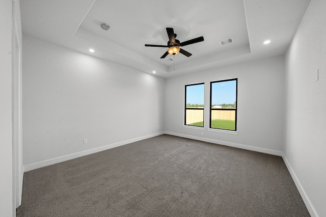 unfurnished room featuring carpet, a tray ceiling, and ceiling fan