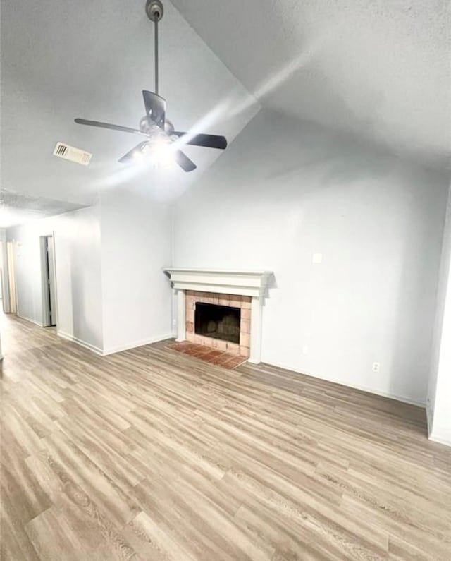 unfurnished living room with lofted ceiling, a fireplace, ceiling fan, and light hardwood / wood-style flooring