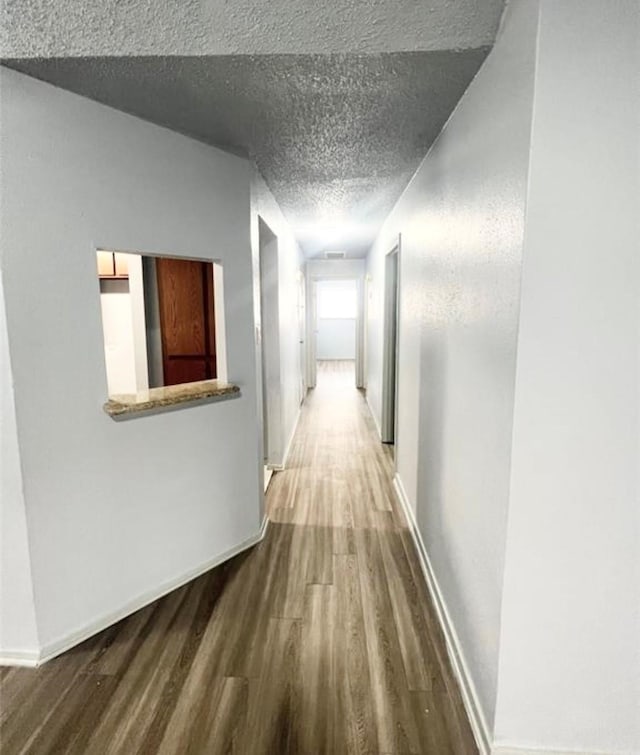 corridor with hardwood / wood-style flooring and a textured ceiling