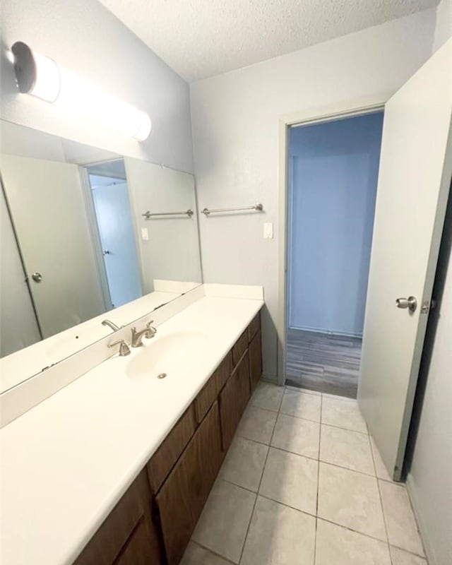 bathroom with tile patterned flooring, vanity, and a textured ceiling