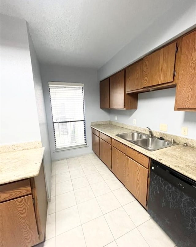 kitchen with light tile patterned floors, black dishwasher, sink, and a textured ceiling