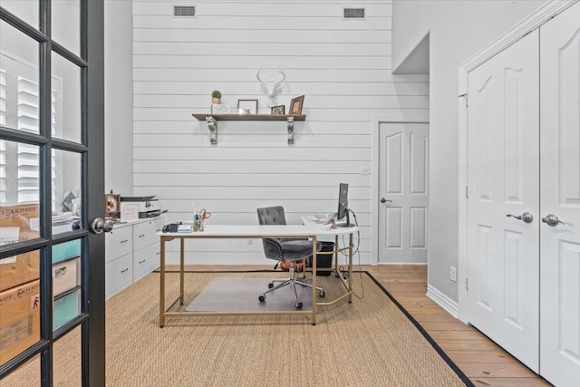 office area with wooden walls and light hardwood / wood-style floors