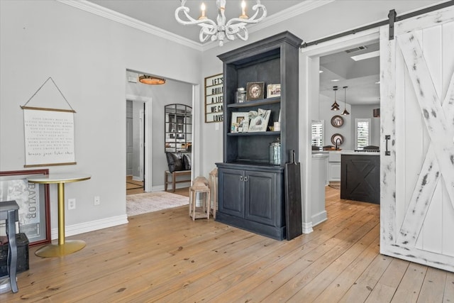 dining room with a barn door, an inviting chandelier, ornamental molding, and light hardwood / wood-style flooring