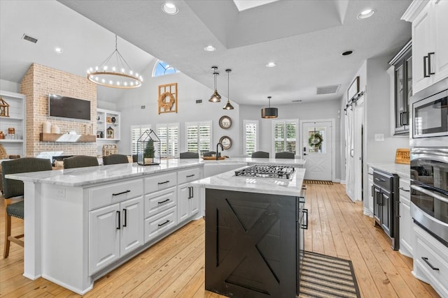 kitchen with a barn door, hanging light fixtures, a kitchen bar, and a center island