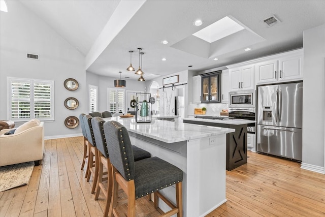 kitchen with stainless steel appliances, a breakfast bar area, a barn door, and a spacious island