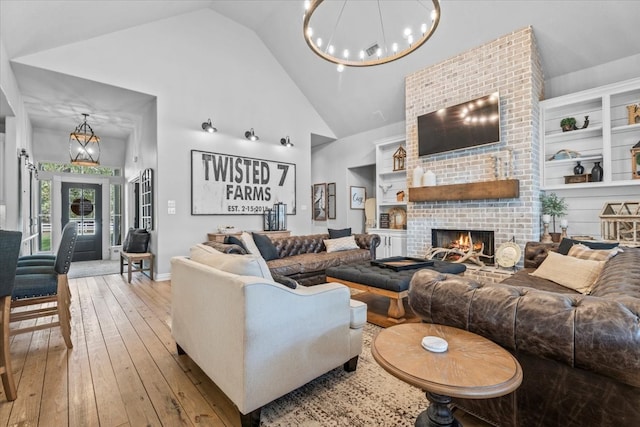 living room with a brick fireplace, high vaulted ceiling, light hardwood / wood-style flooring, and built in features