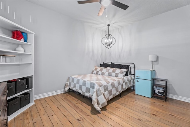 bedroom with ceiling fan with notable chandelier and light wood-type flooring