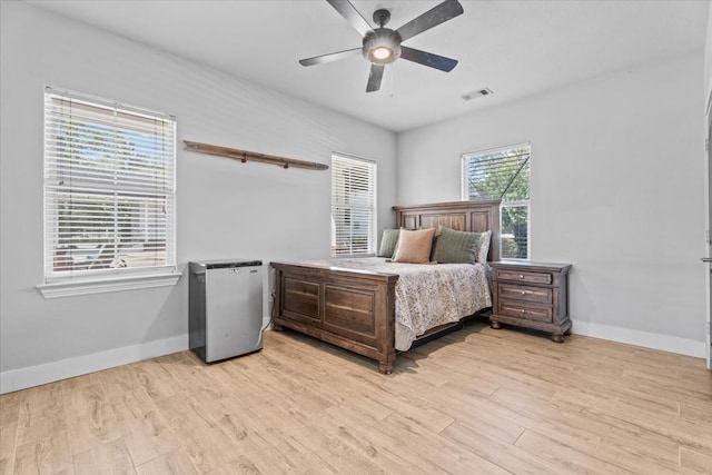 bedroom featuring stainless steel fridge, light wood-type flooring, and ceiling fan