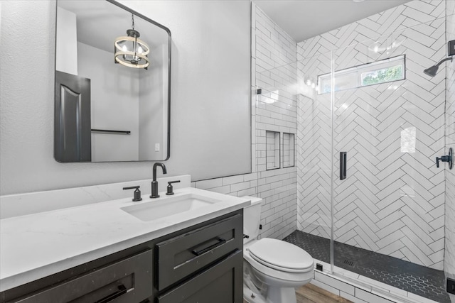 bathroom with vanity, a shower with door, toilet, and an inviting chandelier