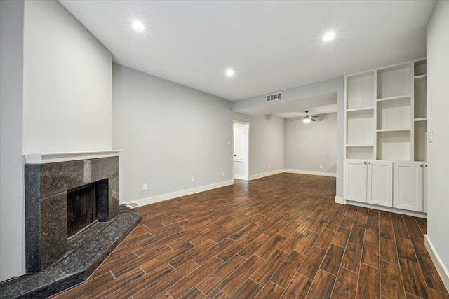 unfurnished living room featuring a fireplace, ceiling fan, and dark wood-type flooring