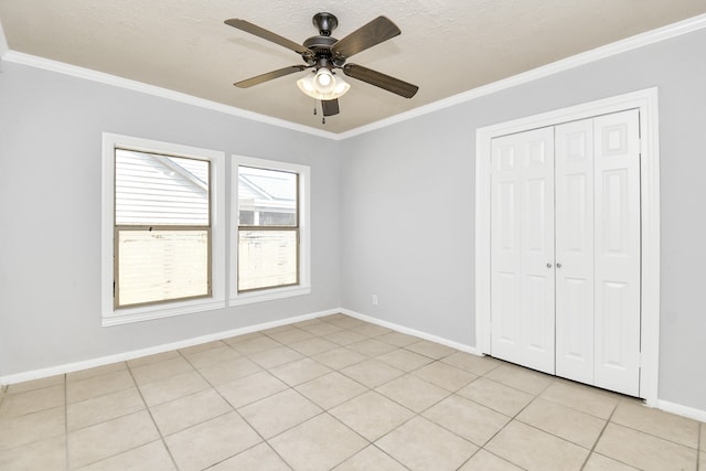 unfurnished bedroom featuring a closet, a textured ceiling, light tile patterned floors, crown molding, and ceiling fan