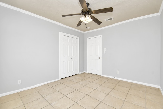 spare room with ceiling fan, light tile patterned floors, a textured ceiling, and ornamental molding