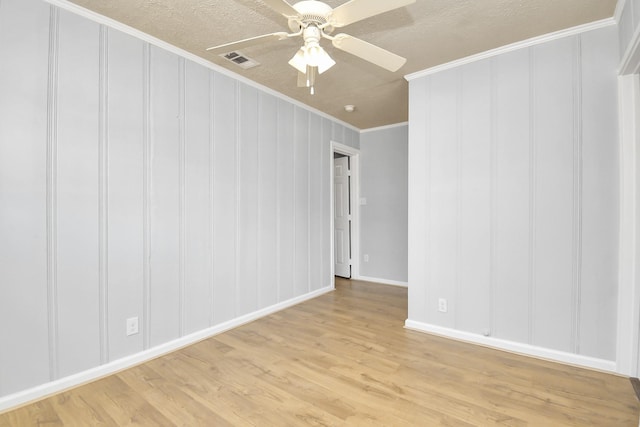 225 N Carolina St, Houston, TX 77029 - unfurnished room with ornamental molding, light wood-type flooring, baseboards, a ceiling fan, and a decorative wall