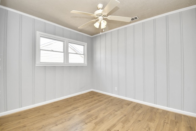 empty room featuring ceiling fan, light wood-type flooring, and crown molding