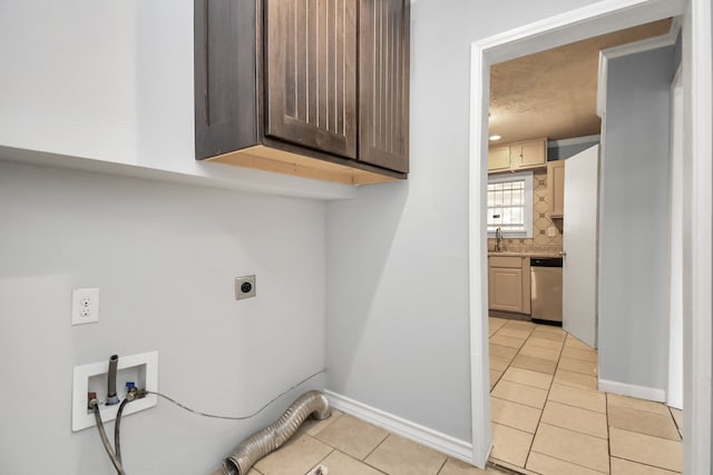 clothes washing area featuring sink, light tile patterned floors, cabinets, hookup for a washing machine, and electric dryer hookup