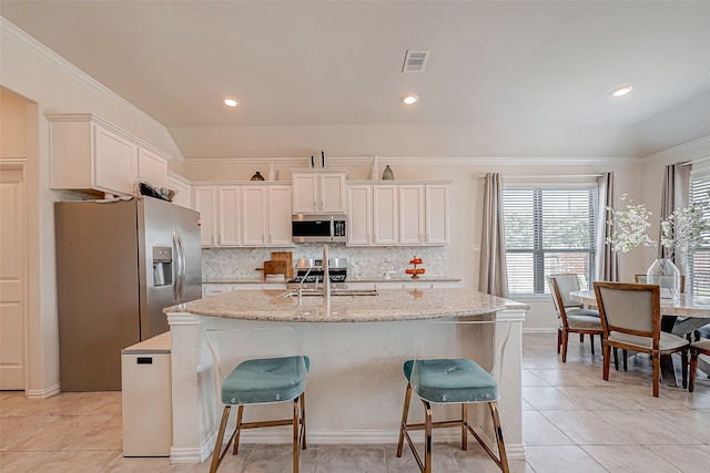 kitchen featuring white cabinets, an island with sink, stainless steel appliances, and a wealth of natural light