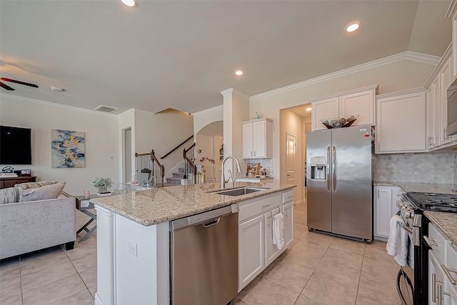 kitchen featuring appliances with stainless steel finishes, white cabinetry, an island with sink, and tasteful backsplash