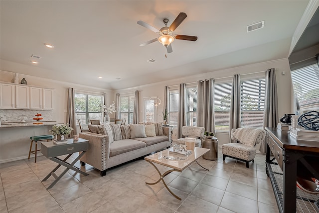 tiled living room with crown molding and ceiling fan