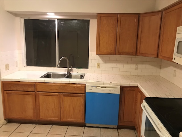 kitchen featuring decorative backsplash, white appliances, light tile patterned floors, tile counters, and sink