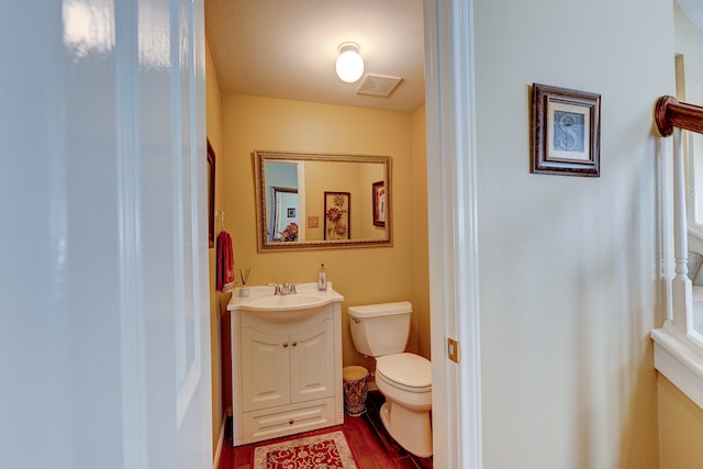 bathroom featuring hardwood / wood-style flooring, vanity, toilet, and a textured ceiling