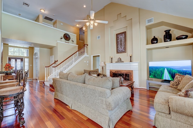 living room with hardwood / wood-style floors, ceiling fan, and high vaulted ceiling