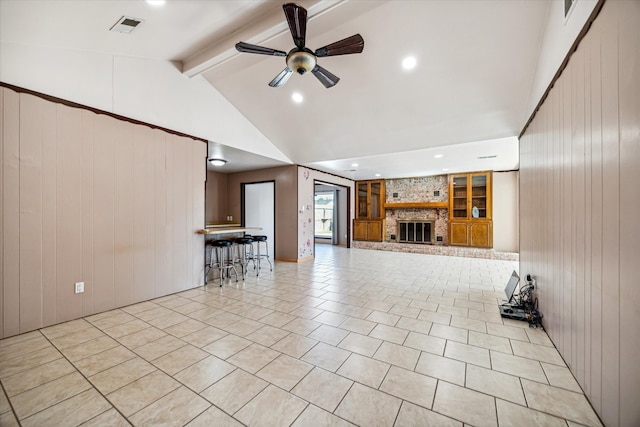 unfurnished living room featuring wooden walls, vaulted ceiling with beams, ceiling fan, and a fireplace