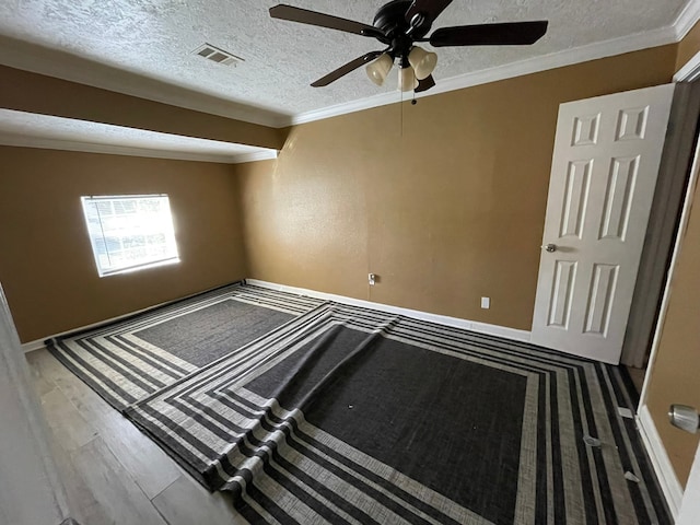 spare room featuring a textured ceiling, wood-type flooring, crown molding, and ceiling fan