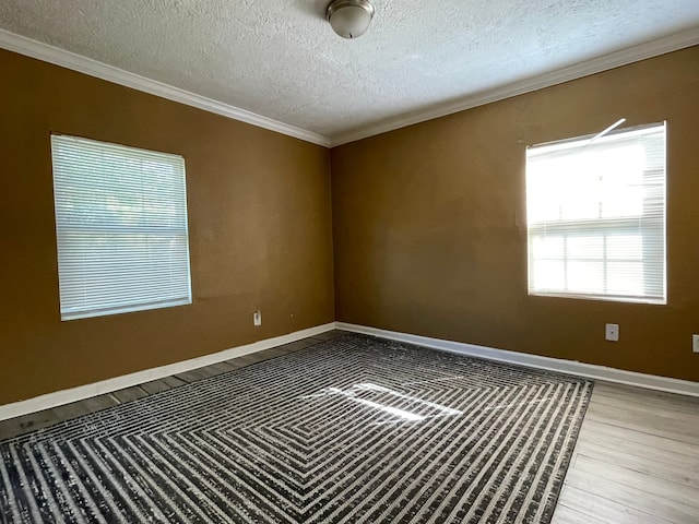 empty room with hardwood / wood-style flooring, ornamental molding, and a textured ceiling