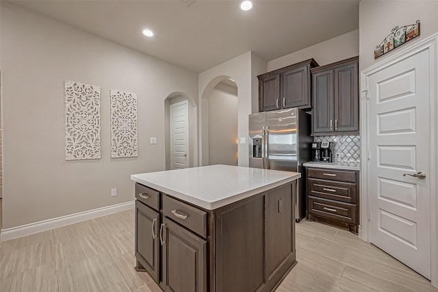 kitchen with dark brown cabinetry, backsplash, a kitchen island, and stainless steel fridge with ice dispenser