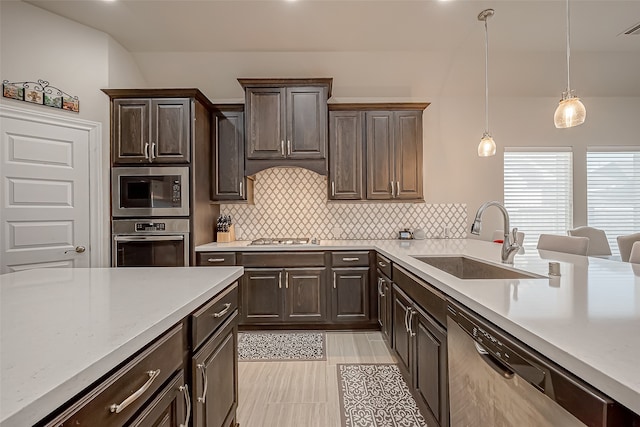 kitchen with stainless steel appliances, decorative light fixtures, dark brown cabinetry, and sink