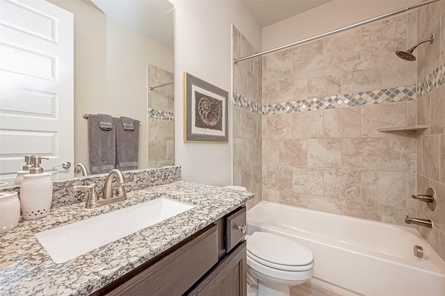 full bathroom featuring vanity, tiled shower / bath combo, and toilet