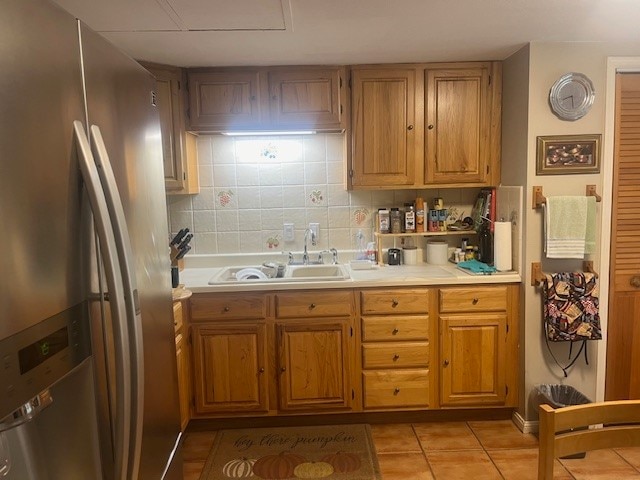 kitchen featuring backsplash, sink, light tile patterned flooring, and stainless steel fridge