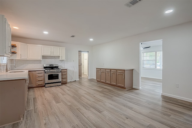 kitchen with stainless steel gas range oven, light wood-type flooring, backsplash, and sink