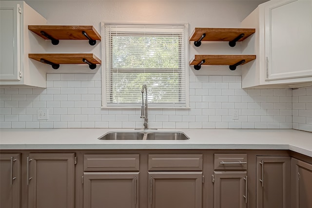 kitchen with decorative backsplash, white cabinetry, and sink