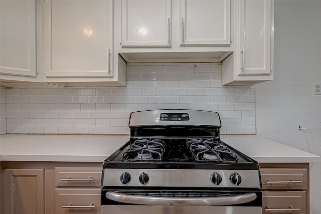 kitchen with decorative backsplash, white cabinets, and stainless steel gas range oven