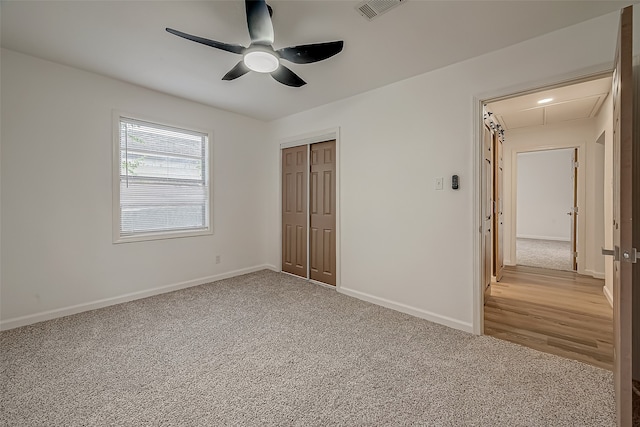 unfurnished bedroom with light wood-type flooring, ceiling fan, and a closet