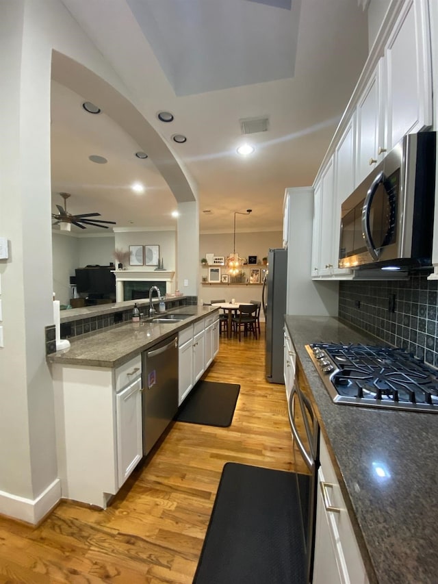 kitchen with appliances with stainless steel finishes, ceiling fan, sink, decorative light fixtures, and white cabinetry