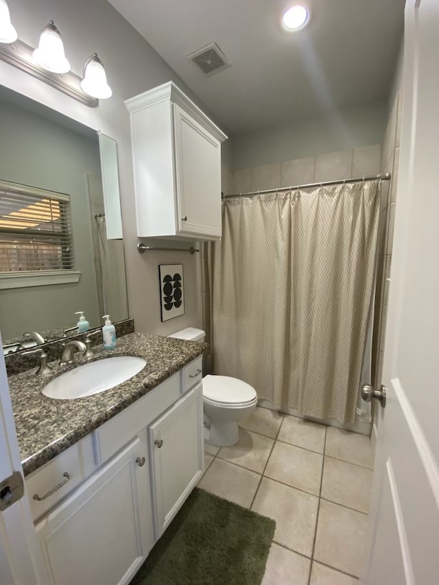 bathroom with tile patterned flooring, vanity, toilet, and walk in shower