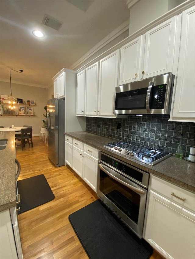 kitchen featuring hanging light fixtures, crown molding, light hardwood / wood-style floors, white cabinets, and appliances with stainless steel finishes