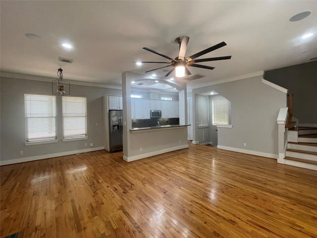 unfurnished living room featuring light hardwood / wood-style flooring, ceiling fan, and ornamental molding