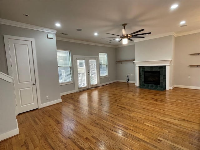 unfurnished living room featuring a tile fireplace, ceiling fan, french doors, wood-type flooring, and ornamental molding