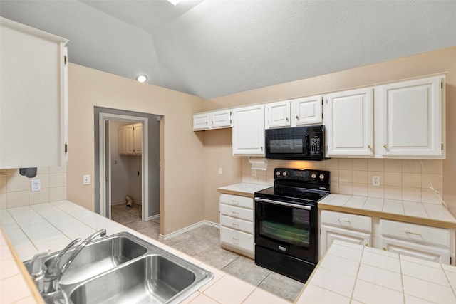 kitchen with black appliances, white cabinets, and tile countertops