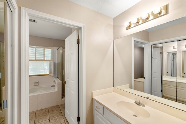 bathroom with tiled tub, vanity, and tile patterned flooring