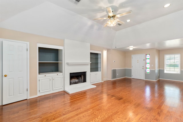 unfurnished living room featuring a fireplace, lofted ceiling, built in features, ceiling fan, and hardwood / wood-style floors