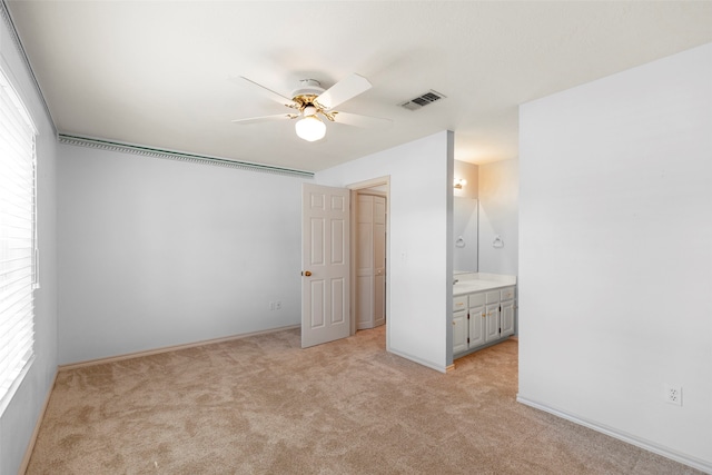 unfurnished bedroom featuring light carpet, ceiling fan, and ensuite bathroom