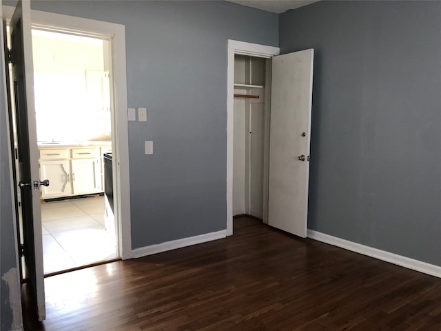 unfurnished bedroom featuring a closet and dark wood-type flooring