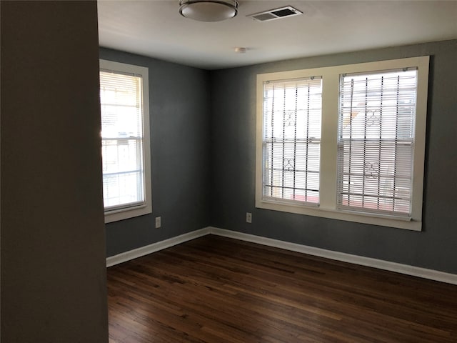 spare room with dark wood-type flooring and a wealth of natural light